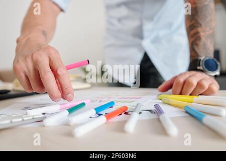 Close-up image of graphic designer using felt tip pens of various color when coloring logo mockup Stock Photo