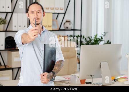 Serious frowning designer with graphic tablet looking at digital pen in his hand Stock Photo