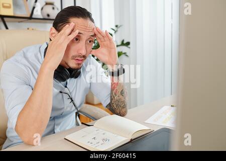 Shocked graphic designer reading confusing clients change requests on computer screen Stock Photo