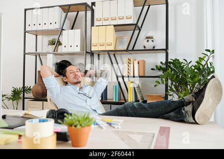 Graphic designer sleeping in his chair when enjoying short break after finishing work on big project Stock Photo