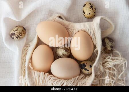 Chicken eggs in a string bag on white background, selective focus. Happy easter background. Stock Photo