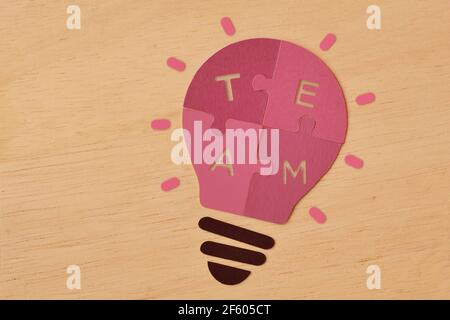 Pink paper light bulb made of puzzle pieces with the word Team - Concept of women and teamwork Stock Photo