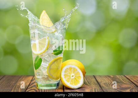 lemonade in glass on wooden table with green blurred background Stock Photo
