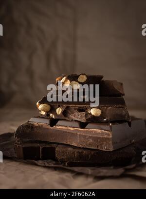 Dark chocolate with almonds and hazelnuts in a stack on brown background Stock Photo