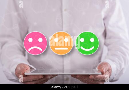 Customer satisfaction concept above a tablet held by a man in background Stock Photo