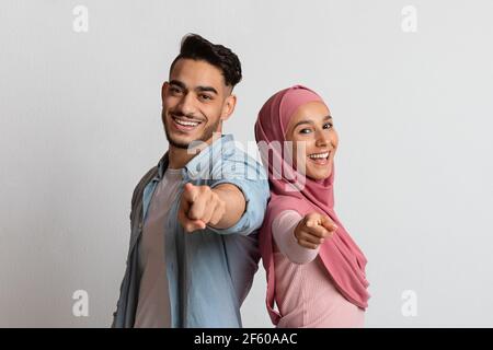 You Are Next. Happy muslim couple pointing at camera and smiling Stock Photo