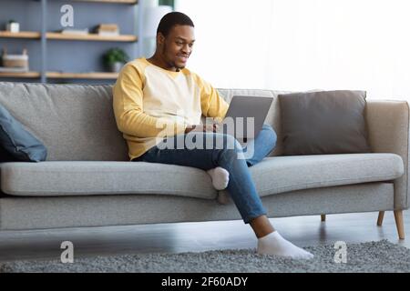Black guy spending time at home, using laptop Stock Photo