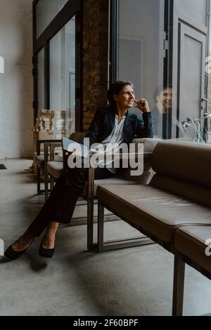 Smiling businesswoman looking through while sitting in office Stock Photo
