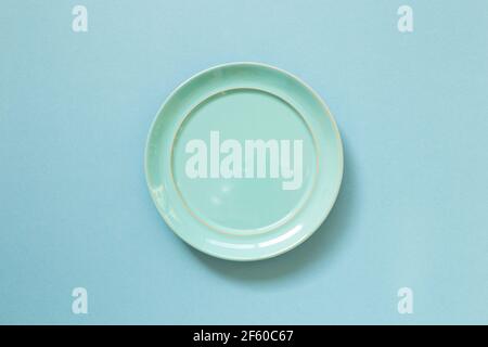 Empty ceramic round plate isolated on blue background. top view Stock Photo