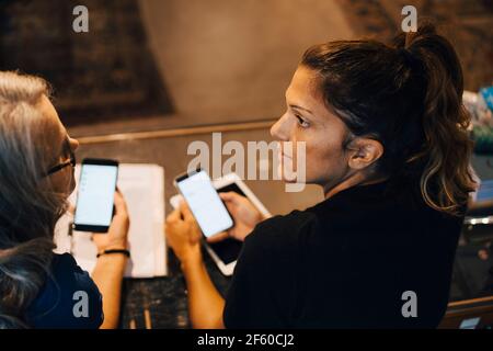 Female colleagues using smart phone in retail store Stock Photo
