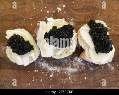 Delicious canapes with black caviar on wooden background Stock Photo