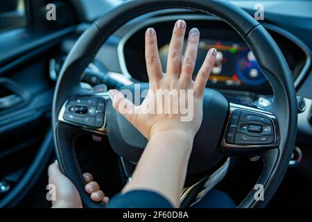 female hand presses the horn on the steering wheel of a modern car. no face Stock Photo