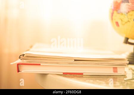 Books, notebooks and globe on the table in sunny room. Stock Photo