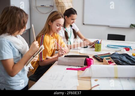 Joyful female children working in sewing workshop Stock Photo
