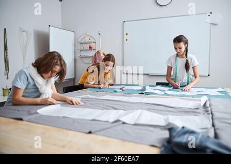 Joyful female kids working in sewing workshop Stock Photo