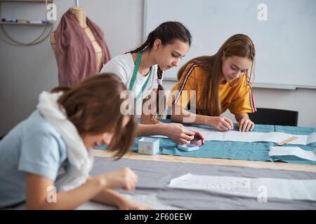 Charming little seamstresses working in sewing workshop Stock Photo