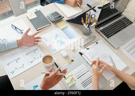 Group of business people discussing charts and diagrams at meeting, analyzing sales data and planning work Stock Photo