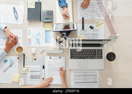 Marketing team working on project at table with charts, documents and gadgets, view from the top Stock Photo