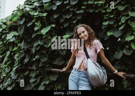 Portrait of woman leaning on railing against plants Stock Photo