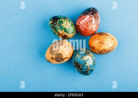 Five easter eggs painted in blue, green, red and yellow lie in a circle. Painted easter eggs on a blue background. Flat lay. Copy space. Stock Photo