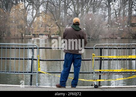 An unidentified middle aged man fishes in the Lake at Kissena Park on a late winter morning. In Flushing, Queens, New York. Stock Photo