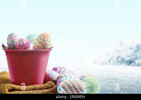 Colorful easter eggs on the nest in a red bucket with fabric on the field. Happy Easter Stock Photo