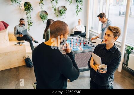 Male and female colleagues talking with each other during break in office Stock Photo