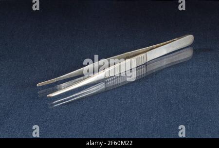 Metal tweezers on a glass table with a reflection. Tools on a black background Stock Photo