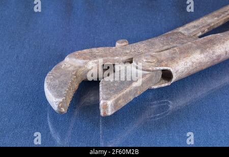 A rusty wrench on a table with a reflection. Locksmith tools on a blue background Stock Photo