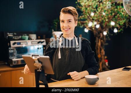 Portrait of smiling female owner with digital tablet in cafeteria Stock Photo