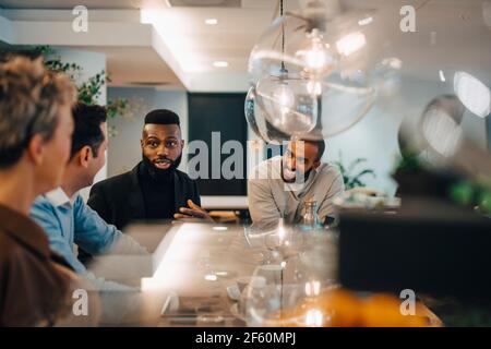 Male entrepreneurs discussing with female colleagues at table in office Stock Photo