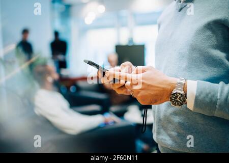 Midsection of businessman using smart phone at office Stock Photo