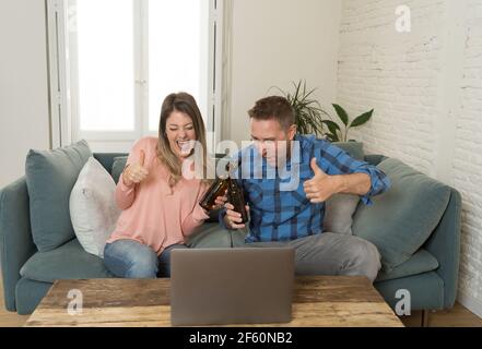 Life at home concept. Happy couple on laptop video calling friends and having an online party at home. Man and woman in video conference or live strea Stock Photo