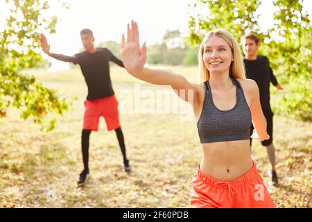 Young people doing aerobics together in fitness class in summer in the park Stock Photo