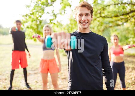 Young people exercising with dumbbells for muscle building in nature Stock Photo
