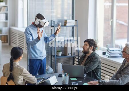 Portrait of diverse IT team developing software for virtual reality project, focus on African-American man wearing VR headset in office Stock Photo