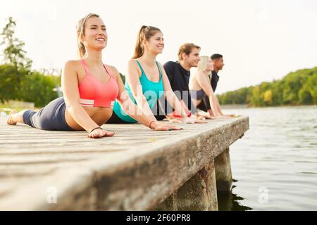Group of young people on the lakeside doing stretching exercise for health and wellness Stock Photo