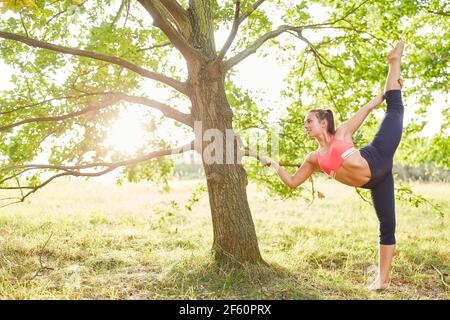 Sporty young woman doing a healthy stretching exercise in nature in summer Stock Photo