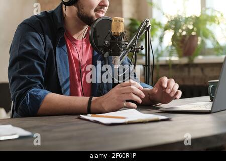 Close-up of radio dj sitting at the table and speaking in microphone while working in recording studio Stock Photo