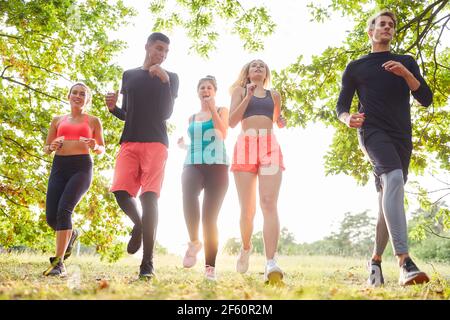 Group of friends jogging together at leisure in nature in summer Stock Photo