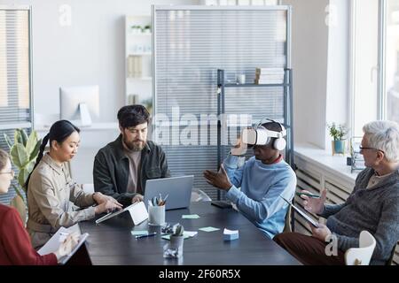 Portrait of diverse IT team developing software for virtual reality project, focus on African-American man using VR in office Stock Photo