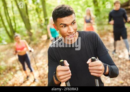 Young man doing nordic walking with friends as fitness and endurance training Stock Photo
