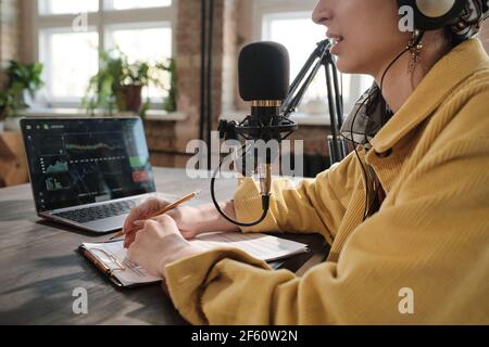 Woman speaking in microphone at the table recording podcast or interview for radio in studio Stock Photo