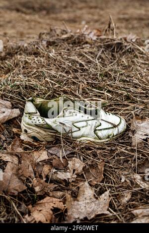 Old torn sneakers in dirty grass Stock Photo