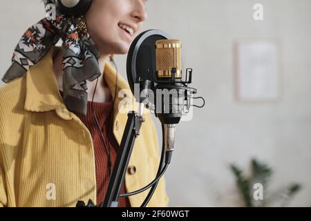 Close-up of woman in headphones singing in microphone and recording a song in studio Stock Photo