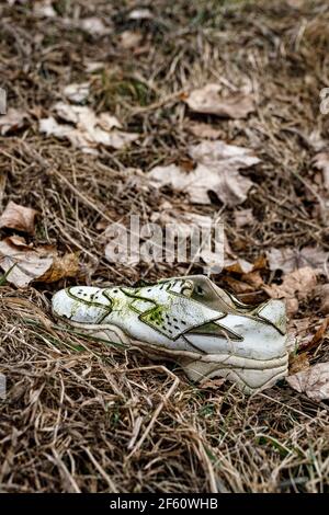Old torn sneakers in dirty grass Stock Photo