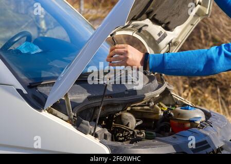 man closes the hood of the car after checking the condition of the car engine. Man inspecting car engine Stock Photo