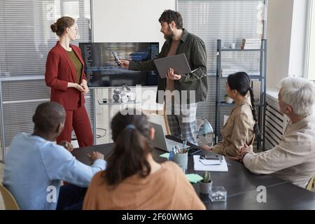 Portrait of modern bearded businessman giving presentation in office to IT team and pointing at code on screen, copy space Stock Photo