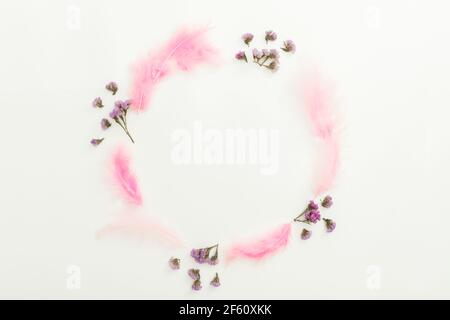Round composition with flowers and pink feathers on white background. Flat lay, top view Stock Photo