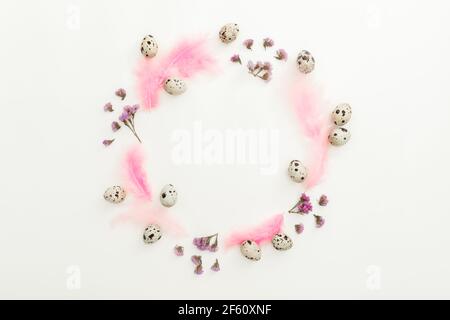 Ester frame composition with quail eggs and pink feathers on white background. Flat lay, top view Stock Photo